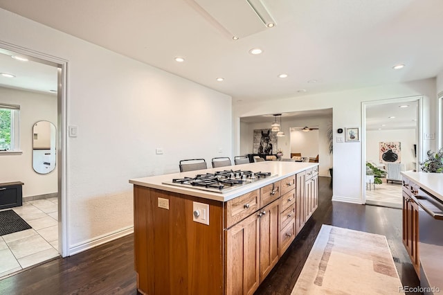 3695 E Dartmouth Ave, Denver, CO 80210 - kitchen with gas stovetop, dark wood-style flooring, stainless steel dishwasher, brown cabinetry, and light countertops