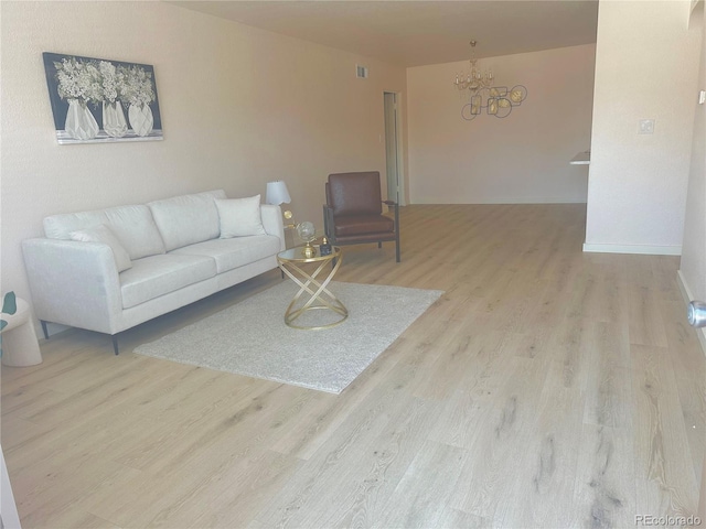 living room featuring a chandelier and light wood-type flooring