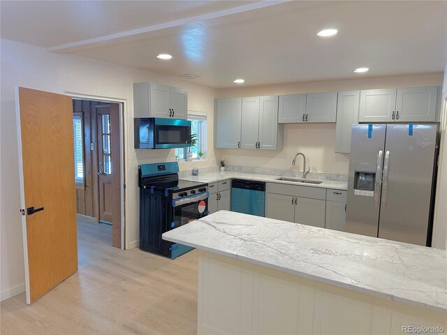 kitchen with stainless steel appliances, a healthy amount of sunlight, sink, and light hardwood / wood-style flooring