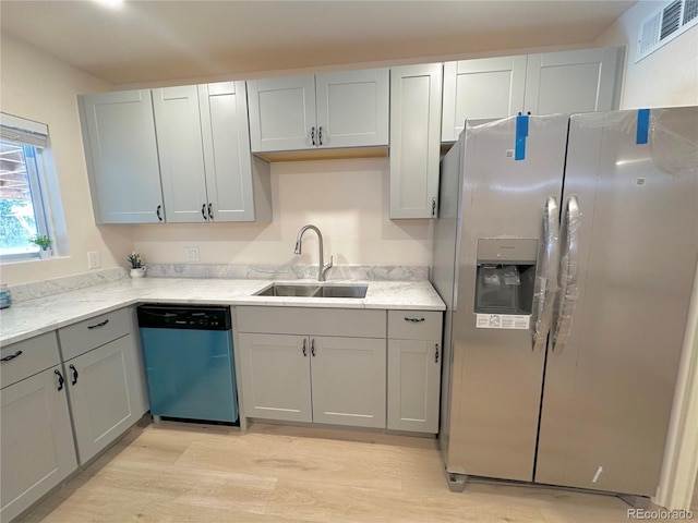 kitchen featuring appliances with stainless steel finishes, sink, gray cabinetry, light stone counters, and light hardwood / wood-style floors