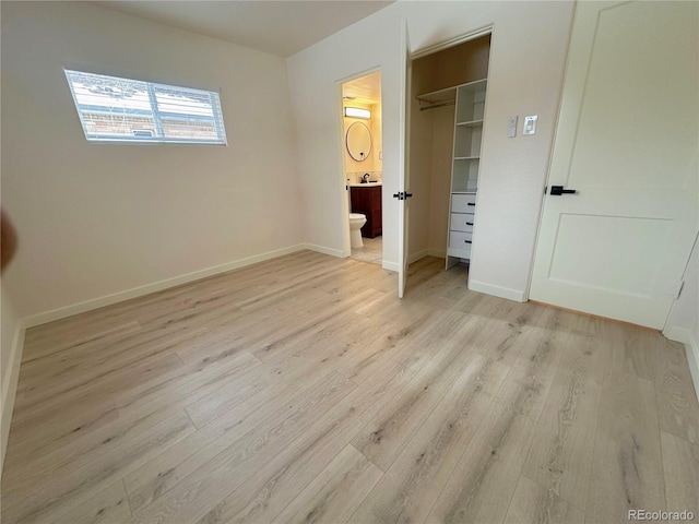 unfurnished bedroom with light wood-type flooring, ensuite bath, and a closet