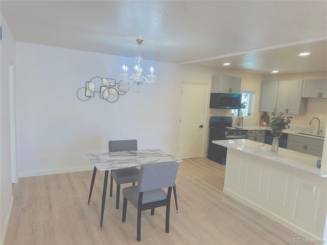 dining area with sink, light hardwood / wood-style floors, and a notable chandelier