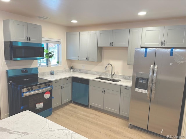 kitchen featuring sink, gray cabinets, stainless steel appliances, light hardwood / wood-style floors, and light stone countertops