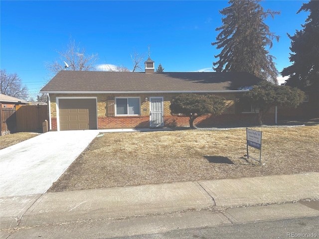 ranch-style house with fence, a shingled roof, concrete driveway, a garage, and brick siding