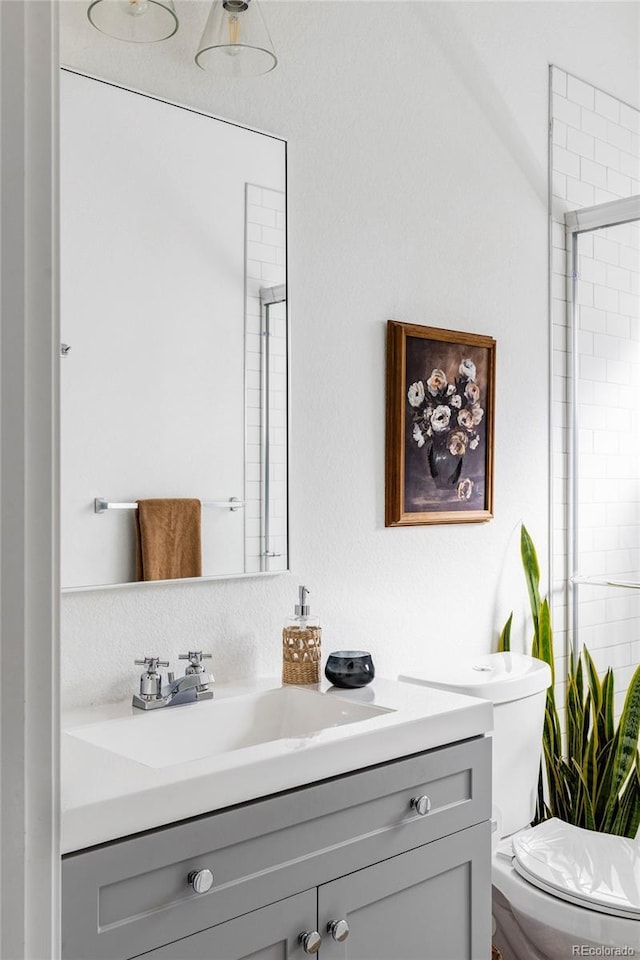 bathroom with a shower with door, vanity, and toilet