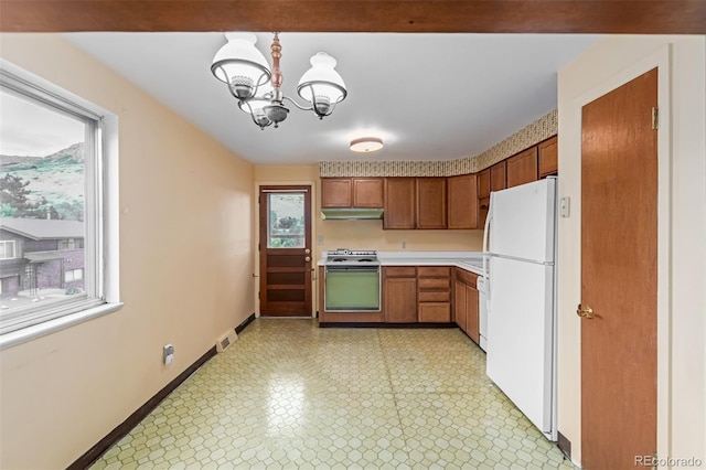 519 N Columbine St, Golden, CO 80403 - kitchen with white appliances, light countertops, under cabinet range hood, light flooring, and a chandelier