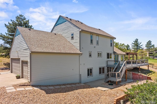 2357 Oak Ridge Rd, Sedalia, CO 80135 - rear view of house with a wooden deck, a garage, roof with shingles, stairway, and driveway