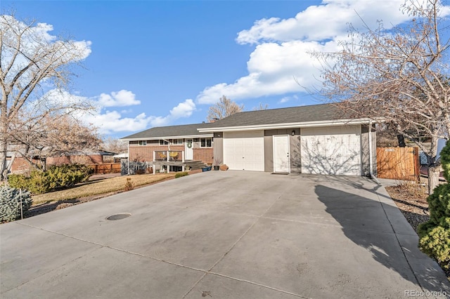 view of front facade featuring driveway, an attached garage, and fence