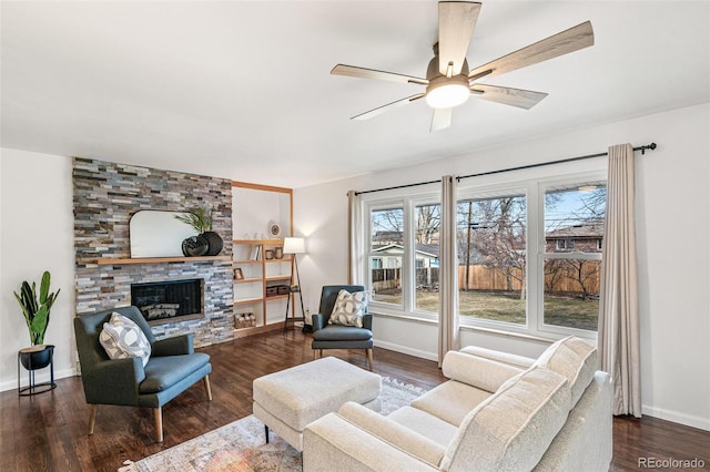 living area with dark wood-style floors, a stone fireplace, and a ceiling fan