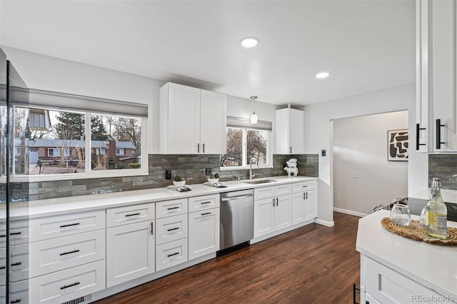 kitchen featuring dark wood-style floors, decorative backsplash, stainless steel dishwasher, white cabinets, and a sink