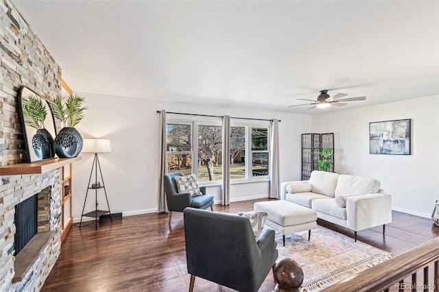 living room featuring ceiling fan, dark wood-type flooring, a fireplace, and baseboards