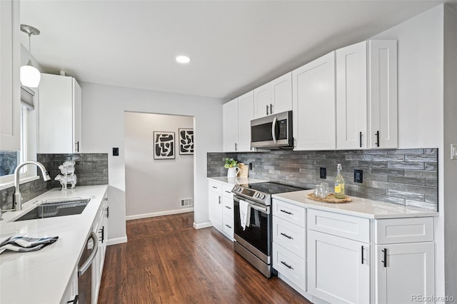 kitchen with baseboards, visible vents, appliances with stainless steel finishes, dark wood-style flooring, and a sink