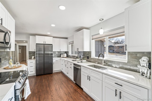 kitchen with a sink, white cabinets, appliances with stainless steel finishes, decorative backsplash, and dark wood-style floors