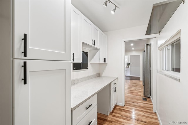 kitchen featuring light stone countertops, light wood finished floors, baseboards, and white cabinets