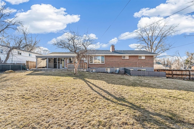 back of house with brick siding, a chimney, a fenced backyard, and a lawn