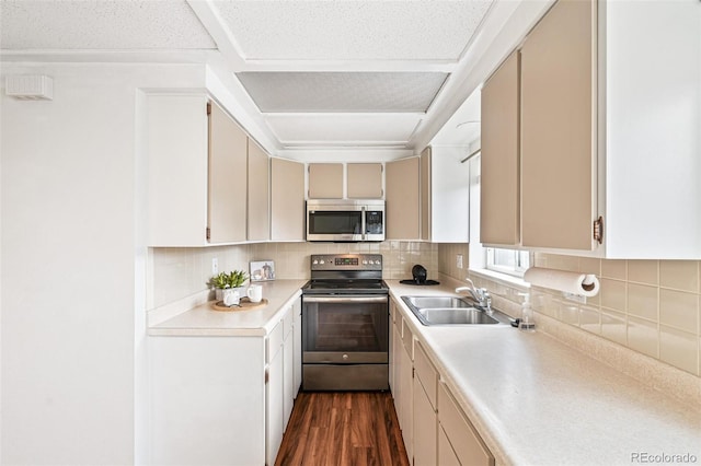 kitchen with dark wood finished floors, tasteful backsplash, light countertops, appliances with stainless steel finishes, and a sink