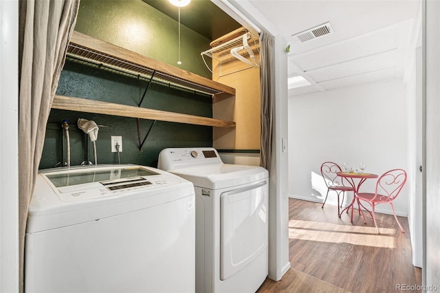 clothes washing area with visible vents, wood finished floors, laundry area, independent washer and dryer, and baseboards