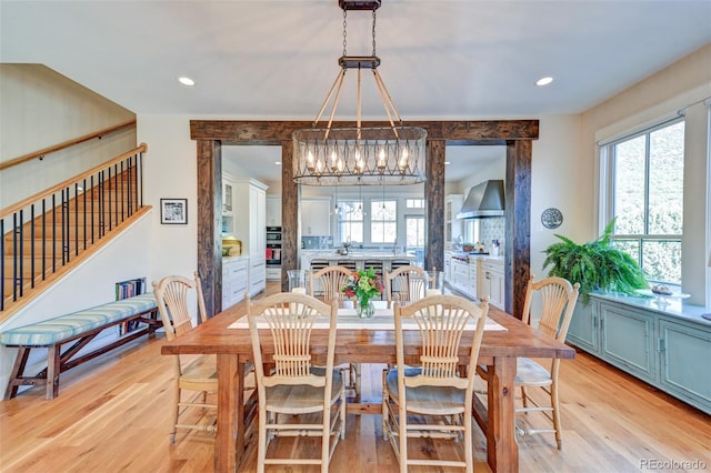 dining area with light wood-type flooring and an inviting chandelier