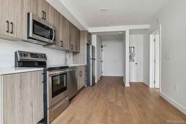 kitchen with light countertops, a sink, appliances with stainless steel finishes, and tasteful backsplash