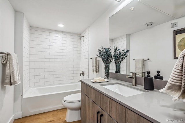 full bathroom featuring toilet, hardwood / wood-style floors, tiled shower / bath combo, and vanity