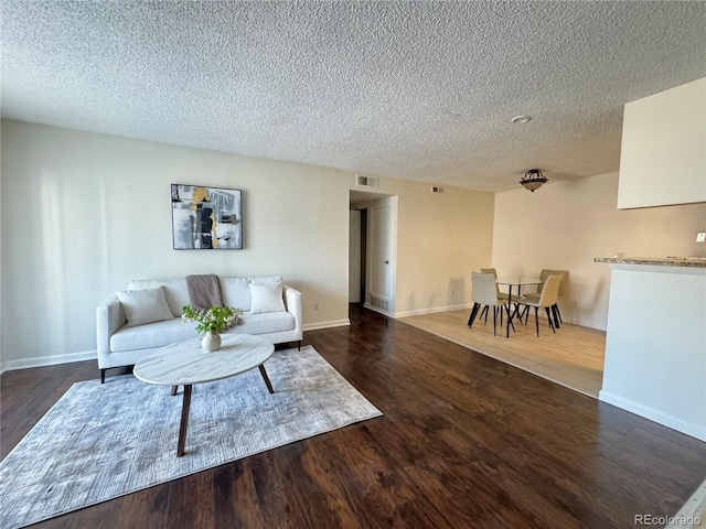 living room with dark hardwood / wood-style flooring and a textured ceiling