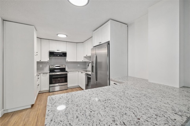 kitchen featuring decorative backsplash, light stone countertops, stainless steel appliances, exhaust hood, and white cabinets