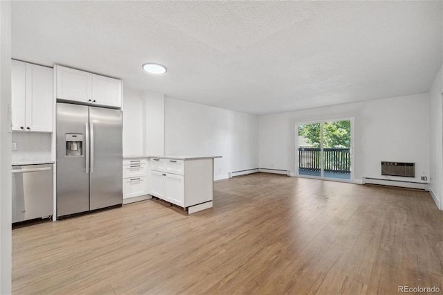 kitchen featuring kitchen peninsula, backsplash, stainless steel appliances, baseboard heating, and white cabinetry