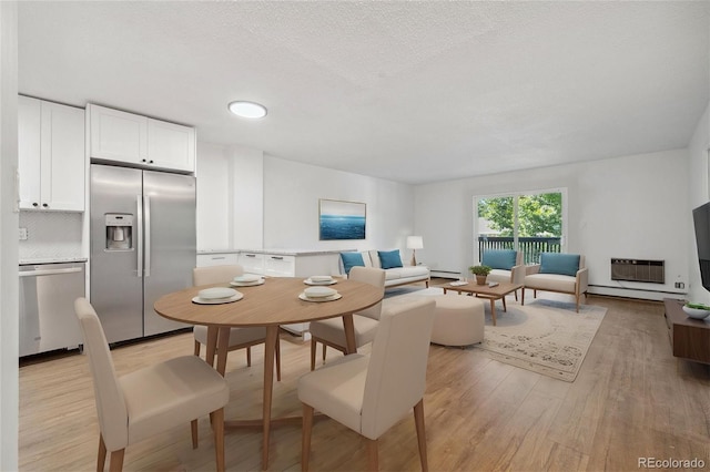 dining space with a textured ceiling, light hardwood / wood-style flooring, and a wall mounted AC