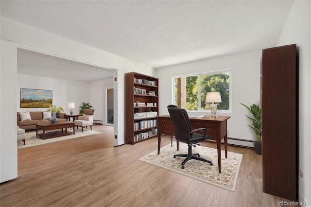 office area with a textured ceiling, light hardwood / wood-style flooring, and a baseboard heating unit