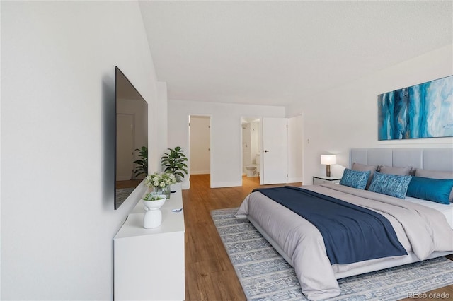 bedroom with wood-type flooring and connected bathroom