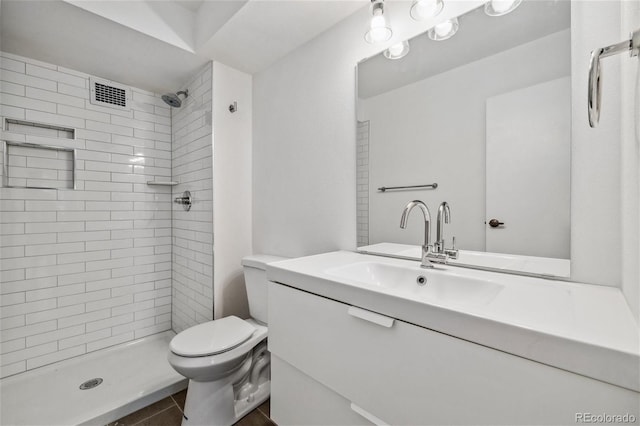 bathroom featuring tile patterned floors, vanity, toilet, and tiled shower