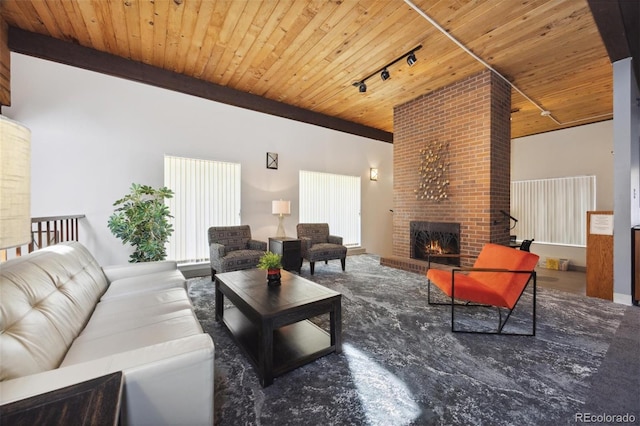 living room featuring rail lighting, a brick fireplace, and wooden ceiling