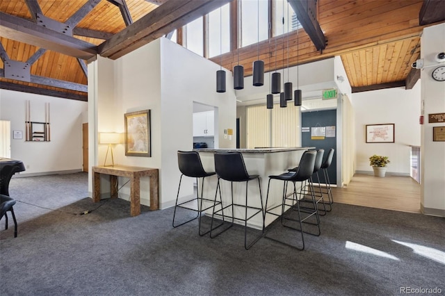 kitchen featuring a towering ceiling, wood ceiling, light colored carpet, beam ceiling, and white cabinetry