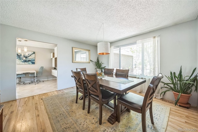 8150 W Calhoun Dr, Littleton, CO 80123 - dining room with a textured ceiling, light wood-style flooring, and a chandelier