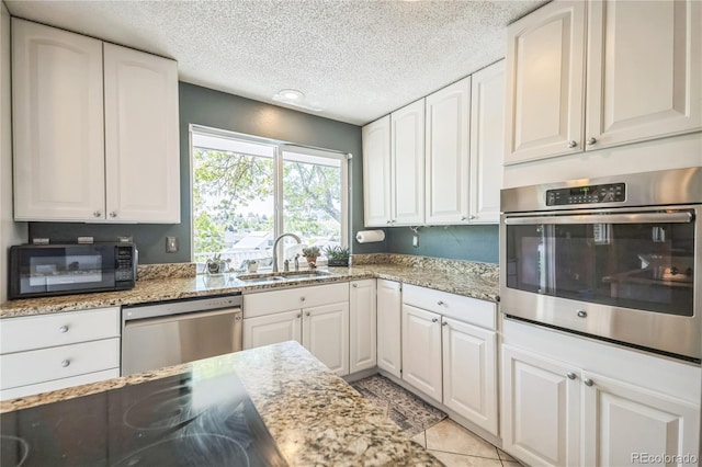 8150 W Calhoun Dr, Littleton, CO 80123 - kitchen with appliances with stainless steel finishes, a sink, a textured ceiling, light stone counters, and white cabinetry