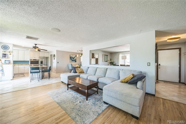 8150 W Calhoun Dr, Littleton, CO 80123 - living room with light wood-style flooring, a textured ceiling, a ceiling fan, and baseboards