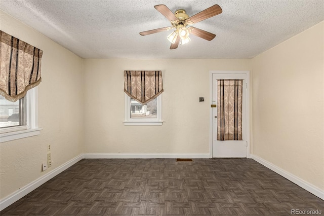 spare room featuring a textured ceiling, a ceiling fan, and baseboards