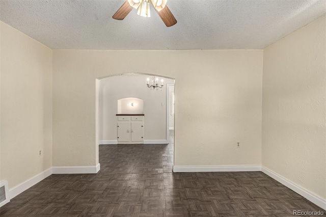 unfurnished room with arched walkways, a textured ceiling, ceiling fan with notable chandelier, and baseboards