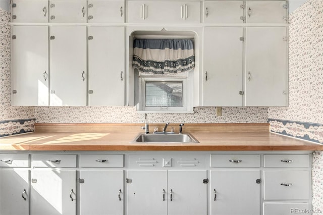 kitchen with light countertops, a sink, and white cabinets