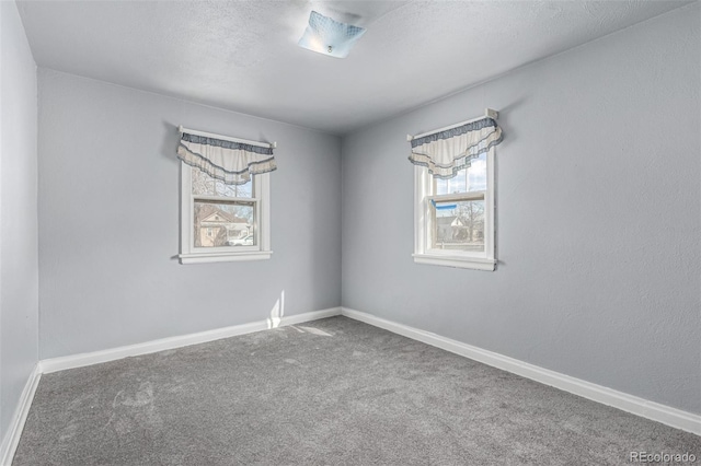 carpeted empty room with a textured ceiling and baseboards