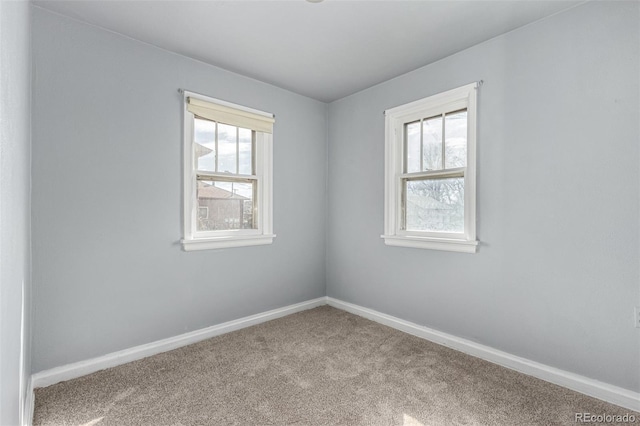 unfurnished room featuring carpet and baseboards