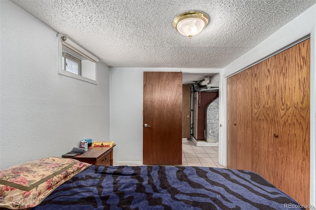 tiled bedroom with a closet, a textured wall, and a textured ceiling