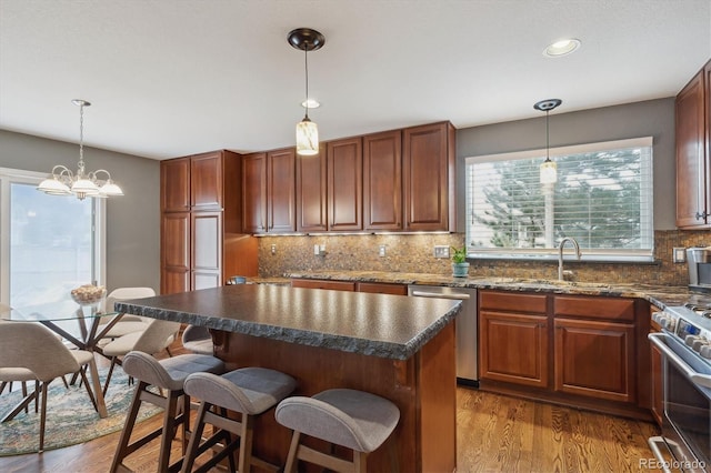 kitchen featuring a kitchen breakfast bar, backsplash, a kitchen island, dark wood finished floors, and stainless steel appliances