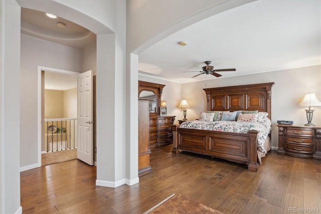 bedroom with dark wood-style floors, arched walkways, and baseboards