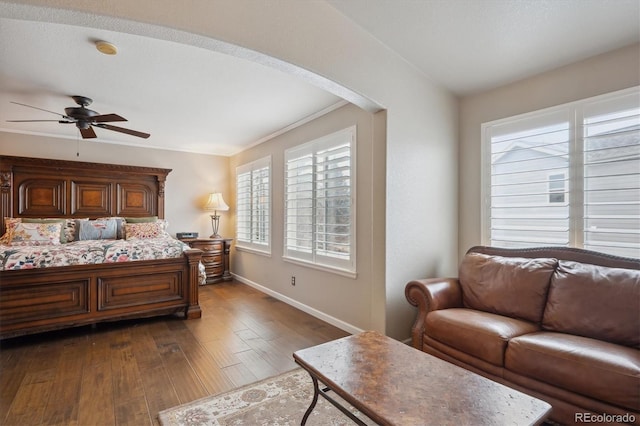 bedroom with multiple windows, dark wood-style floors, arched walkways, and baseboards