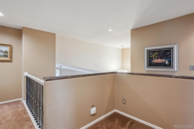 hall featuring baseboards, an upstairs landing, and carpet flooring