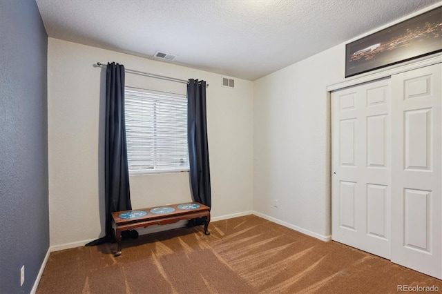 unfurnished bedroom with visible vents, carpet flooring, a textured ceiling, and baseboards