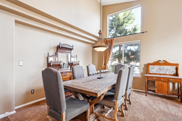 dining space with baseboards, carpet floors, and a high ceiling