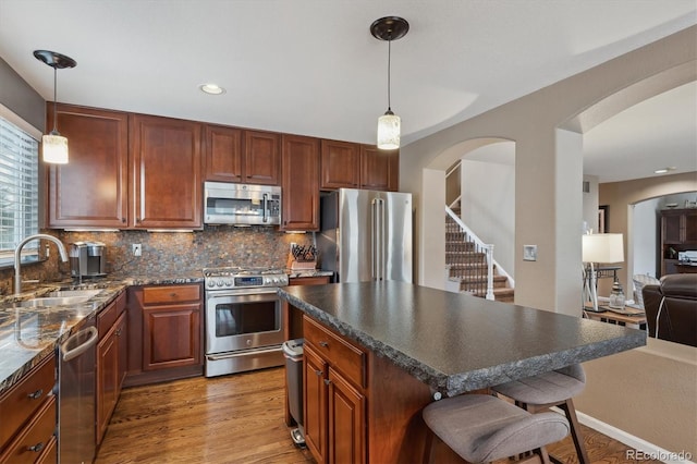 kitchen featuring backsplash, a kitchen breakfast bar, light wood-style floors, stainless steel appliances, and a sink