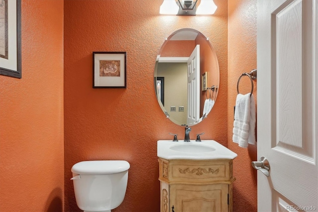 bathroom featuring vanity, toilet, and a textured wall